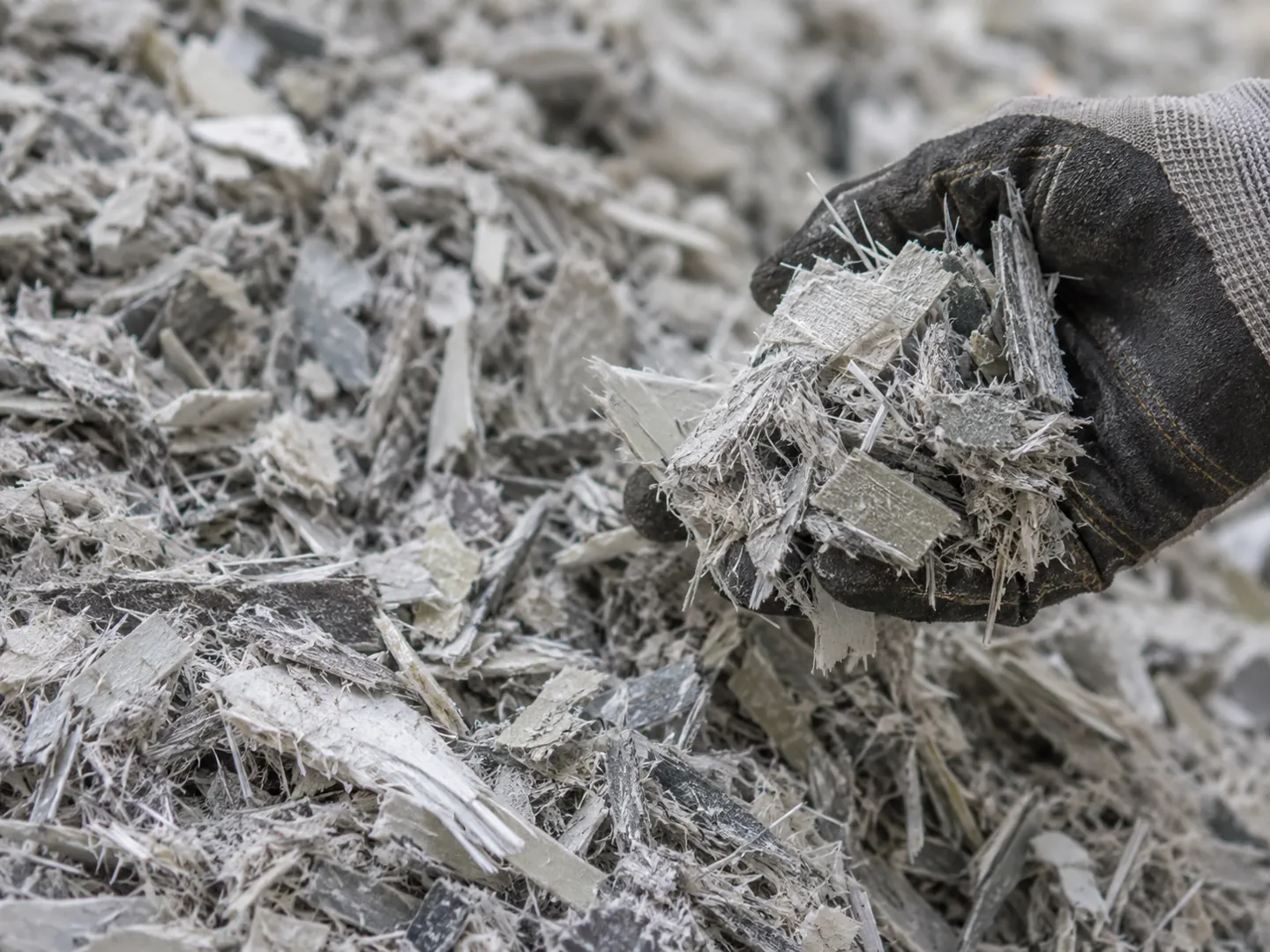 Close-up of grey shredded fibreglass composite pieces in a heap, the kind of material left after an old blade is ground down
